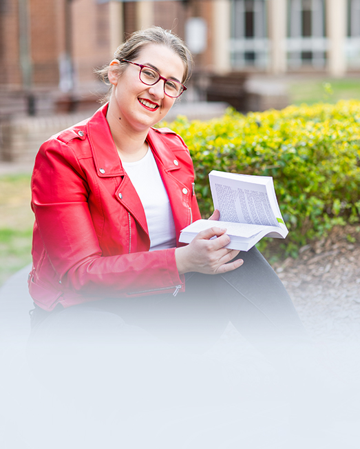 Helena Citroni sitting in the campus gardens reading.