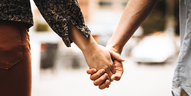 A close up of man and a woman holding hands