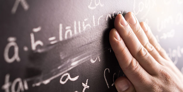Teacher wiping chalk across blackboard