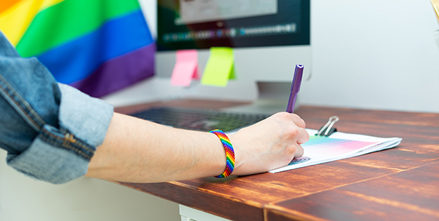 Office worker with rainbow wristband writing