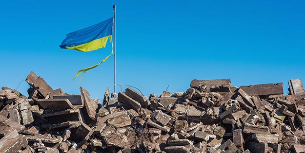 Ukrainian flag flying over rubble