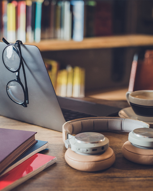 An open laptop with glasses resting on top and a cup of coffee.