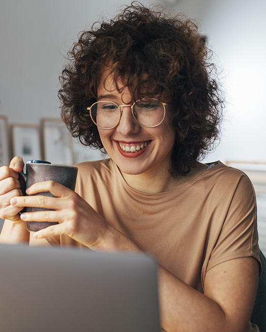 Woman in glasses smiling at laptop computer