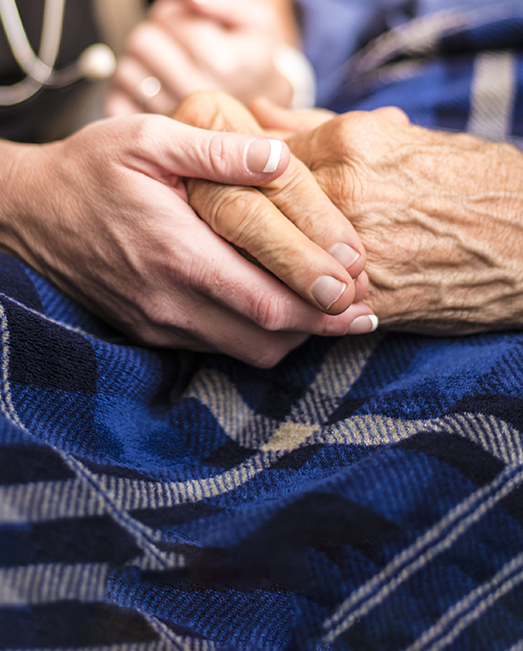 Nurse holding old woman's hand