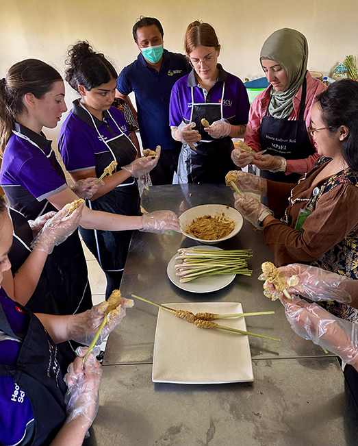 ACU students with teacher cooking Indonesian food