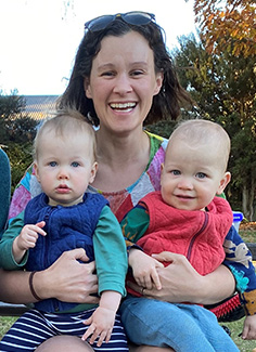 Dr Evelyn Parr smiling at camera while holding twin babies