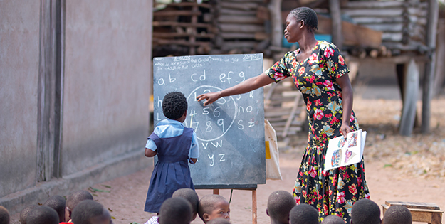 Woman in Malawi at chalkboard with child