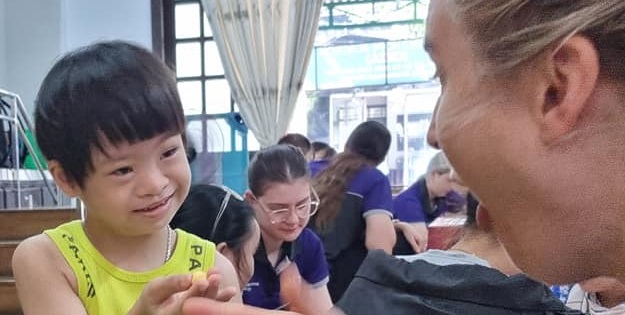 Smiling Vietnamese child and ACU OT student.
